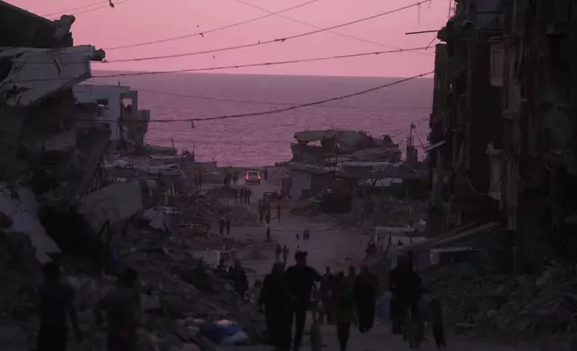 Palestinians walk between destroyed buildings in Gaza City, Wednesday, June 3, 2026. (AP Photo/Jehad Alshrafi)