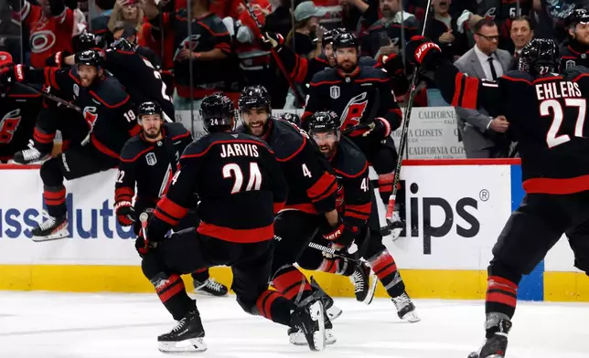 Carolina Hurricanes' Seth Jarvis (24) celebrates after his winning goal with teammates Shayne Gostisbehere (4), and Jordan Martinook (48) with Nikolaj Ehlers (27) nearby following the overtime period in Game 2 of the NHL hockey Stanley Cup Final series against the Vegas Golden Knights in Raleigh, N.C., Thursday, June 4, 2026. (AP Photo/Karl DeBlaker)