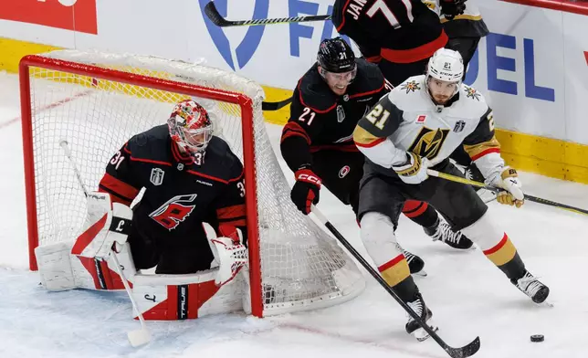 Vegas Golden Knights' Brett Howden, right, handles the puck ahead of Carolina Hurricanes' Alexander Nikishin, middle, and goaltender Frederik Andersen (31) during the second period of Game 1 of the NHL hockey Stanley Cup Final series in Raleigh, N.C., Tuesday, June 2, 2026. (AP Photo/Ben McKeown)