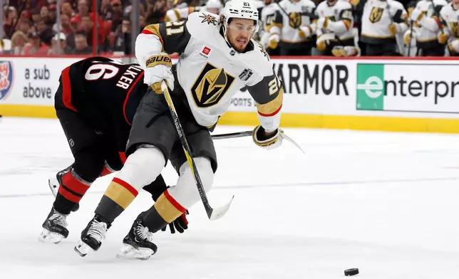Vegas Golden Knights' Brett Howden (21) battles with Carolina Hurricanes' Sean Walker (26) on his way to scoring a goal during the first period in Game 2 of the NHL hockey Stanley Cup Final series in Raleigh, N.C., Thursday, June 4, 2026. (AP Photo/Karl DeBlaker)