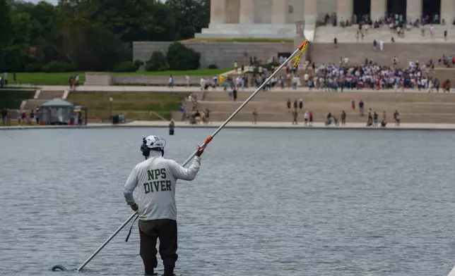 A National Park Service employee works to clean the Lincoln Memorial Reflecting Pool Sunday, June 21, 2026, on the National Mall in Washington. (AP Photo/Jon Elswick
