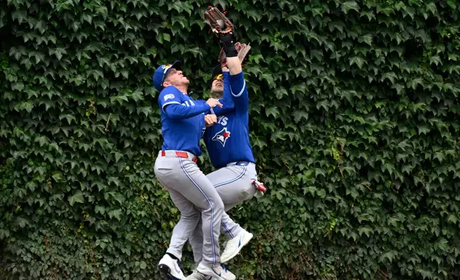 Toronto Blue Jays right fielder Myles Straw, left, and center fielder Dulton Varsho collide as Varsho' makes the catch on a fly ball hit by Chicago Cubs' Miguel Amaya during the fourth inning of a baseball game, Saturday, June 20, 2026, in Chicago. (AP Photo/Matt Marton)