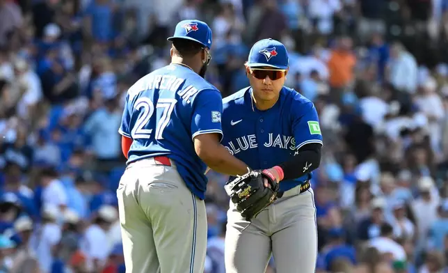 Toronto Blue Jays first baseman Vladimir Guerrero Jr. (27) and third baseman Kazuma Okamoto, right, of Japan, hug after a baseball game against the Chicago Cubs, Saturday, June 20, 2026, in Chicago. (AP Photo/Matt Marton)