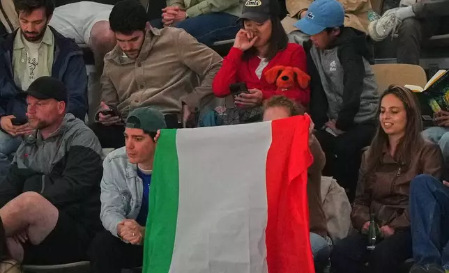 Fans hold an Italian flag during the quarterfinal tennis match between Canada's Felix Auger-Aliassime and Italy's Flavio Cobolli at the French Open in Paris, Wednesday, June 3, 2026. (AP Photo/Aurelien Morissard)