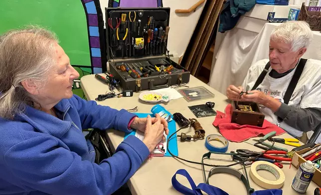 Bob Morton, a former IBM electrical engineer, right, repairs a 1930s-era Hammond clock for Paula Weinstein, at a Repair Café in New Paltz, N.Y., May 23, 2026. (AP Photo/Michael Weissenstein)