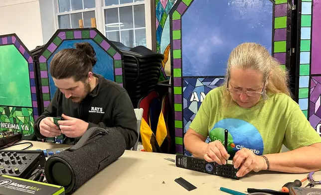 Electronic repair coach Dan Casey and his mother Diane Casey work on a sound-mixing device at a Repair Café in New Paltz, N.Y., May 23, 2026. (AP Photo/Michael Weissenstein)