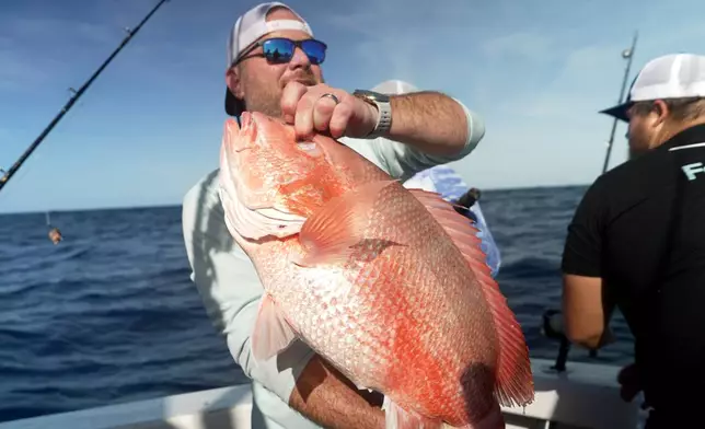 Chris Kemp holds up a red snapper he caught on the charter boat Jodie Lynn II, before releasing it back into the water miles off the coast of St. Augustine, Fla., on May 22, 2026. (AP Photo/Shelby Lum)