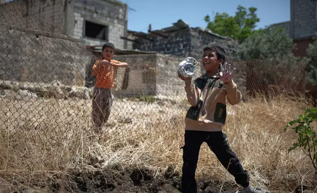 A local boy plays with the remains of an exploded Israeli shell as another boy looks on in the village of Abdin, Daraa province, Syria, Monday, June 29, 2026. (AP Photo/Ghaith Alsayed)