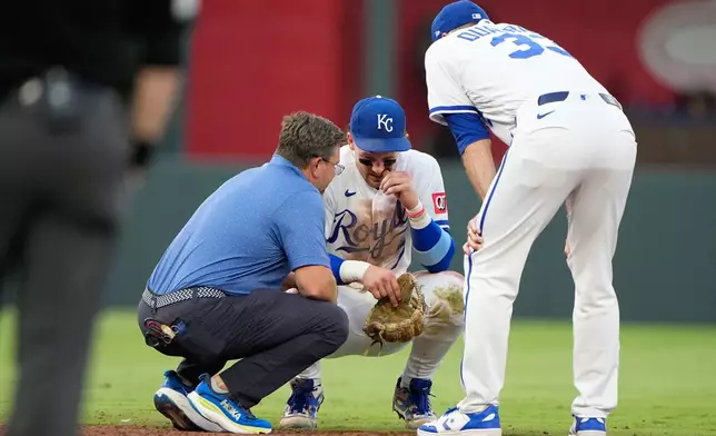 Kansas City Royals shortstop Bobby Witt Jr. talks to manager Matt Quatraro, right, and trainer Kyle Turner, left, after getting injured while fielding a single by St. Louis Cardinals' Jordan Walker during the fourth inning of a baseball game Thursday, June 18, 2026, in Kansas City, Mo. (AP Photo/Charlie Riedel)