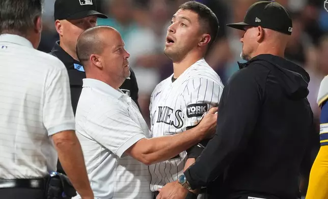 Colorado Rockies' Tyler Freeman, center, is tended to by trainer Heath Townsend, center left, as manager Warren Schaeffer, right, looks on after he was hit on the helmet by a pitch from Milwaukee Brewers starter Jacob Misiorowski in the sixth inning of a baseball game Saturday, June 6, 2026, in Denver. (AP Photo/David Zalubowski)