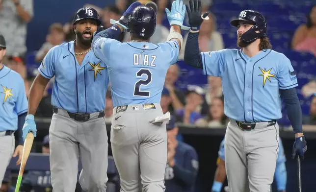 Tampa Bay Rays' Junior Caminero, left, and Yandy Díaz (2) celebrate after scoring on a triple by Richie Palacios during the first inning of a baseball game against the Miami Marlins Friday, June 5, 2026, in Miami. (AP Photo/Marta Lavandier)
