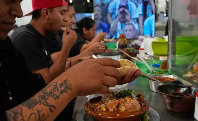 Workers eat at the Juarez market where a monitor shows the World Cup soccer match between Argentina and Austria in Mexico City, Monday, June 22, 2026. (AP Photo/Marco Ugarte)
