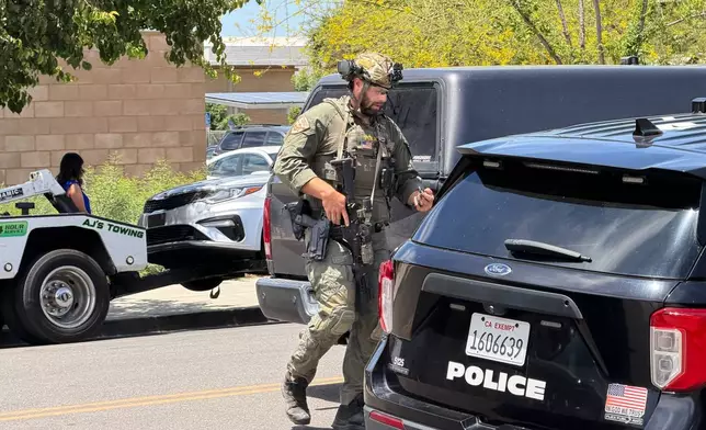 A law enforcement officer responds near a bank where a man barricaded himself on Tuesday, June 2, 2026, in Bakersfield, Calif. (Jacob, Dad’s Gone Live via AP)