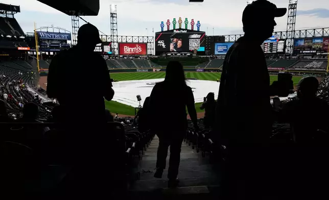 A tarp covers the infield as baseball fans wait during a rain delay before a baseball game between the Atlanta Braves and the Chicago White Sox in Chicago, Thursday, June 11, 2026. (AP Photo/Nam Y. Huh)