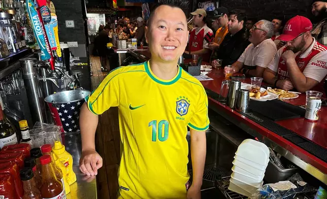 Lion Sports Bar owner Mark Prinzinger poses behind the bar as fans watch a Champion league soccer match between Arsenal and Paris Saint-Germain, Saturday, May 30, 2026, in Philadelphia. (AP Photo/Tassanee Vejpongsa)
