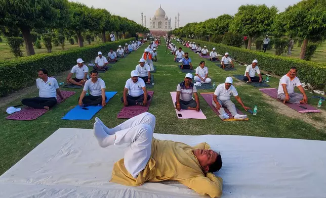 People perform yoga during an International Yoga Day event against the backdrop of the Taj Mahal in Agra, India, Sunday, June 21, 2026. (AP Photo/ Pawan Sharma)