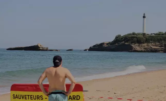 A tourist looks towards a massive section of coastline which collapsed Wednesday evening, killing one diver and leaving another missing, in Biarritz, Thursday, June 25, 2026. (AP Photo/Yohan Bonnet)