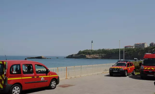 Rescue cars are parked near a massive section of coastline which collapsed Wednesday evening, killing one diver and leaving another missing, in Biarritz, Thursday, June 25, 2026. (AP Photo/Yohan Bonnet)