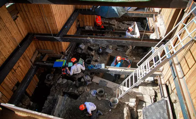 Archaeological workers wearing hard hats dig 4 meters (13 feet) underground during excavations outside Notre-Dame Cathedral in Paris, Monday, June 1, 2026. (AP Photo/Nicolas Garriga)