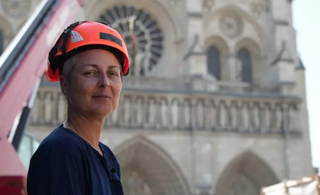 Camille Colonna, archaeologist in charge of operations, wearing a safety helmet, poses in front of Notre-Dame Cathedral during excavations in Paris, Monday, June 1, 2026. (AP Photo/Nicolas Garriga)