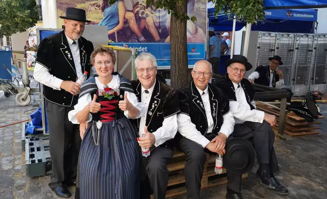 A group of yodellers stay cool in the shade outside the Martins church in Basel, Switzerland, Saturday, June 27, 2026. (AP Photo/Jez Fielder)