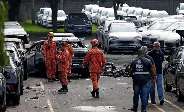 Emergency workers inspect the site where two helicopters reportedly collided in midair and crashed into a car dealership parking lot in Rio de Janeiro, Brazil, Sunday, June 14, 2026. (AP Photo/Bruna Prado)