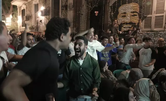 Fans celebrate after Egypt scored the first goal as they watch a broadcast of the World Cup soccer match between Egypt and Belgium at a coffee shop in Cairo, Egypt, Monday, June 15, 2026. Background graffiti shows Egyptian soccer star, Mohamed Salah. (AP Photo/Amr Nabil)