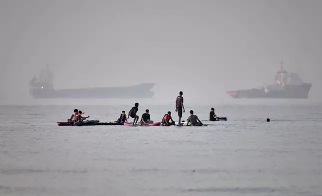 People gather on paddleboards in shallow water as cargo and service vessels are anchored in the Strait of Hormuz off Bandar Abbas, Iran, Monday, June 1, 2026. (Amirhosein Khorgooi/ISNA via AP)