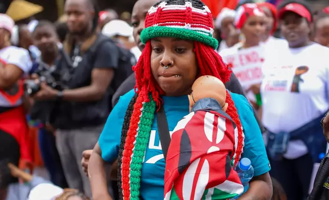 A demonstrator holds a doll wrapped in a Kenyan flag, during a march against rising cases of femicide, in downtown Nairobi, Kenya, on Monday, June 1, 2026. (AP Photo/Patrick Ngugi)
