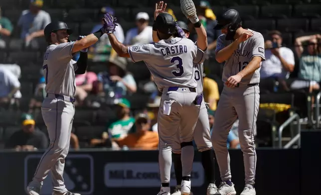 Colorado Rockies' Willi Castro (3), center, is greeted by teammates after hitting a grand slam during the eighth inning of a baseball game against the Athletics, Sunday, June 14, 2026, in Las Vegas. (AP Photo/Caroline Brehman)