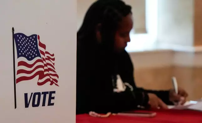 A Fulton County staff member works as people vote in a runoff election, Tuesday, June 16, 2026, in Atlanta. (AP Photo/Mike Stewart)