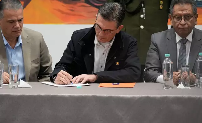 Bolivian President Rodrigo Paz signs legislation approved by Congress establishing the legal framework for a state of emergency at the government palace, accompanied by his Defense Minister Ernesto Justiniano, left, and Minister of Government Marco Antonio Oviedo in La Paz, Bolivia, Monday, June 8, 2026. (AP Photo/Juan Karita)