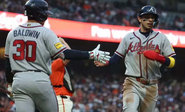 Atlanta Braves' Mauricio Dubón, right, is congratulated by Drake Baldwin (30) after scoring on a single by Ozzie Albies during the third inning of a baseball game against the San Francisco Giants in San Francisco, Friday, June 26, 2026. (AP Photo/Jed Jacobsohn)