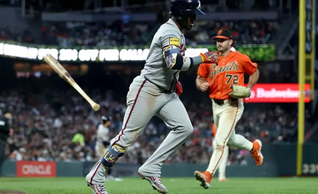 Atlanta Braves' Ozzie Albies, center, runs to first after hitting an RBI sacrifice fly in front of San Francisco Giants pitcher Trevor McDonald (72) during the fifth inning of a baseball game in San Francisco, Friday, June 26, 2026. (AP Photo/Jed Jacobsohn)