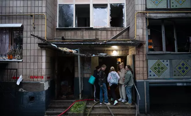 Local residents gather near the entrance to a damaged residential building following an overnight Russian attack in Kyiv, Ukraine, Monday, June 15, 2026. (AP Photo/Danylo Antoniuk)