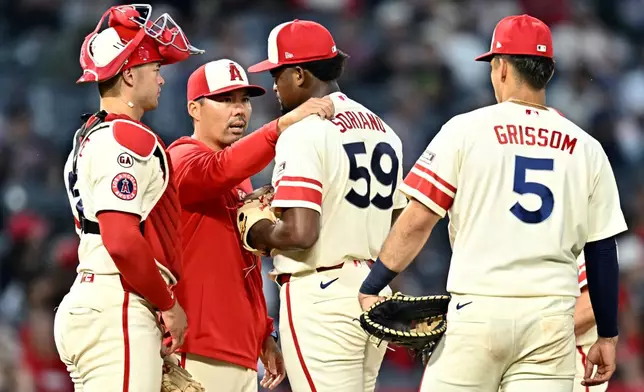 Los Angeles Angels manager Kurt Suzuki, second from left, speaks with pitcher José Soriano (59) before a pitching change during the fifth inning of a baseball game against the Colorado Rockies, Monday, June 1, 2026, in Anaheim, Calif. (AP Photo/William Liang)