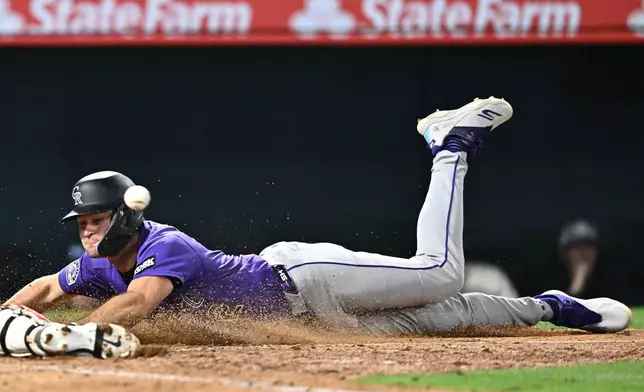 Colorado Rockies' Kyle Karros dives safely to score during the eighth inning of a baseball game against the Los Angeles Angels, Monday, June 1, 2026, in Anaheim, Calif. (AP Photo/William Liang)