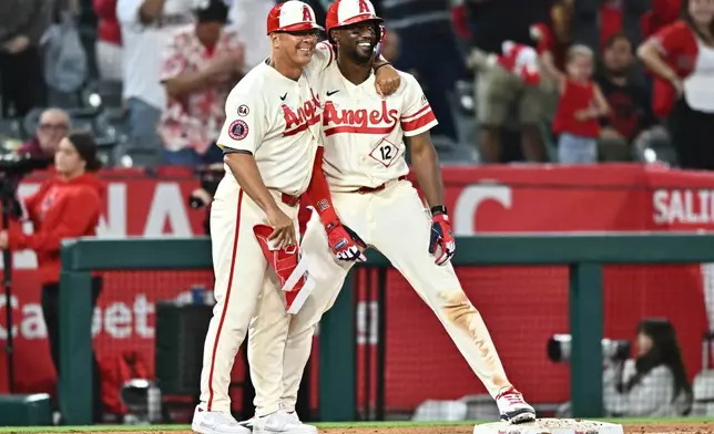 Los Angeles Angels' Jorge Soler, right, is greeted by third base coach Keith Johnson after hitting an RBI triple during the eighth inning of a baseball game against the Colorado Rockies, Monday, June 1, 2026, in Anaheim, Calif. (AP Photo/William Liang)