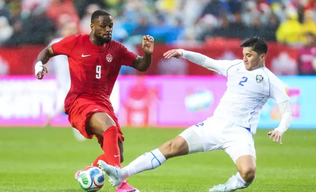 Canada's Cyle Larin (9) has the ball kicked away by Uzbekistan's Abdukodir Khusanov (2) during the first half of an international friendly soccer match in Edmonton, Alberta, Monday, June 1, 2026. (Codie McLachlan/The Canadian Press via AP)