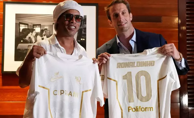 Brazilian football legend Ronaldinho, left, holds up jerseys along with Ignazio Cipriani, president of Ravenna FC, at a media event celebrating Ronaldinho's recent signing with the Italian soccer club, at Cipriani Downtown Miami restaurant, Tuesday, June 23, 2026, in Miami. (AP Photo/Rebecca Blackwell)