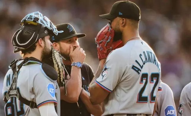 Miami Marlins pitching coach Daniel Moskos, second from left, confers with starting pitcher Sandy Alcantara (22) and catcher Joe Mack, left, in the third inning of a baseball game against the Colorado Rockies, Monday, June 29, 2026, in Denver. (AP Photo/David Zalubowski)