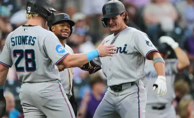 From left to right, Miami Marlins' Kyle Stowers and Xavier Edwards congratulate pinch hitter Griffin Conine after Conine's three-run home run off Colorado Rockies relief pitcher Victor Vodnik in the fifth inning of a baseball game Monday, June 29, 2026, in Denver. (AP Photo/David Zalubowski)