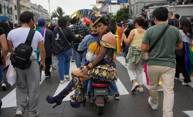 A participant blows a kiss while riding sidesaddle on a motorcycle during the Pride march in Lima, Peru, Saturday, June 27, 2026. (AP Photo/Martin Mejia)