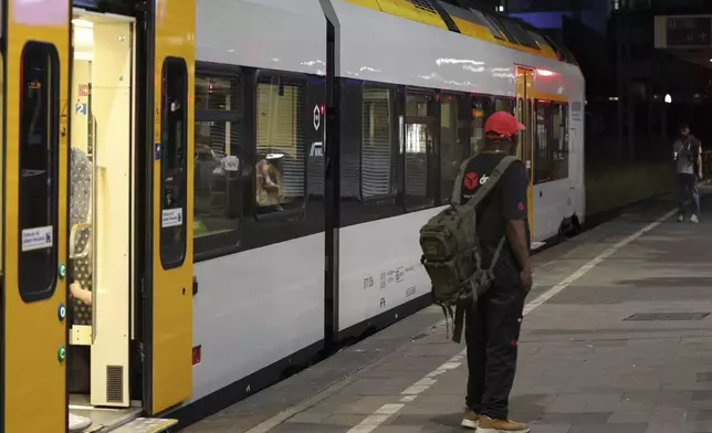A passenger stands on a platform in front of a train at Duisburg Central Station, Tuesday, June 23, 2026. (Christoph Reichwein/dpa via AP)