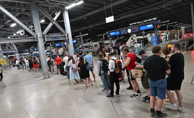 Passengers stand in line at the DB information desk at the Munich train station, Tuesday, June 23, 2026. (Peter Kneffel/dpa via AP)