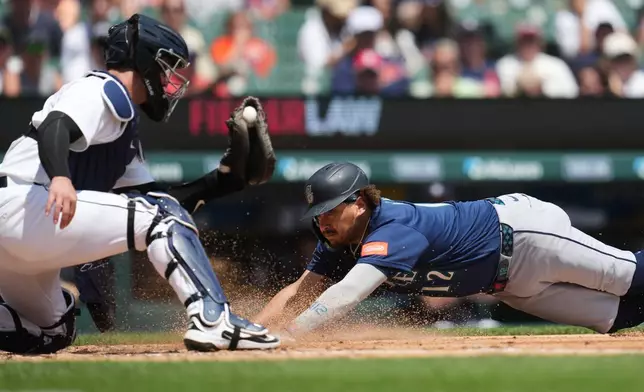 Seattle Mariners' Josh Naylor, right, slides safely into home plate ahead of the tag of Detroit Tigers catcher Dillon Dingler, left, during the third inning of a baseball game Saturday, June 6, 2026, in Detroit. (AP Photo/Paul Sancya)