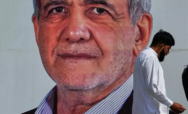A man walks past a welcoming billboard featuring Iranian President Masoud Pezeshkian along a roadside in Islamabad, Pakistan, Tuesday, June 23, 2026. (AP Photo/Anjum Naveed)