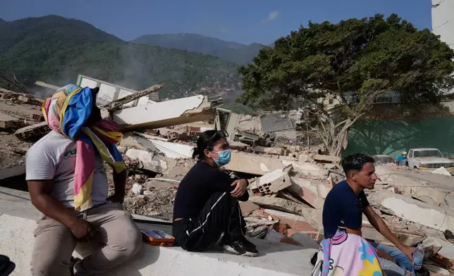 Residents sit near their destroyed homes two days after an earthquake struck La Guaira, Venezuela, Friday, June 26, 2026. (AP Photo/Ariana Cubillos)