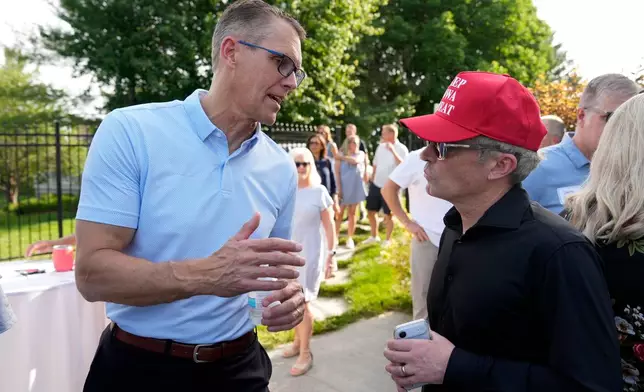 Rep. Randy Feenstra, R-Iowa, talks with Eric Branstad, right, as he campaigns for the Republican nomination for governor during a rally with local residents, Wednesday, May 27, 2026, in West Des Moines, Iowa. (AP Photo/Charlie Neibergall)