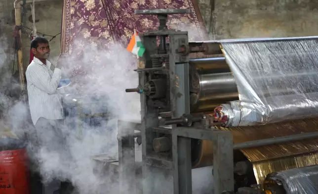 Steam comes out of a machine near a worker at a textile factory on a hot day in Sachin near Surat, India, Wednesday, May 27, 2026. (AP Photo/Ajit Solanki)